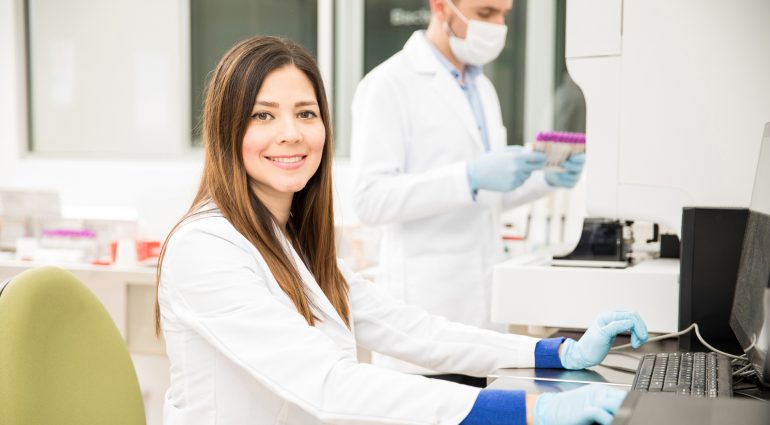 Laboratory technician at terminal, smiling at camera